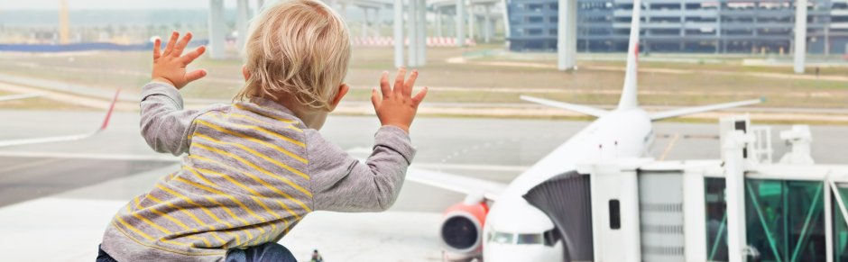 jongetje voor raam kijkt naar vliegtuig